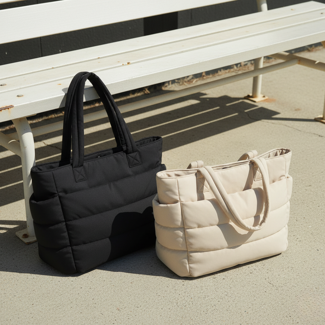 „Czarna i kremowa torba Softi stoją obok siebie przy białej ławce na zewnątrz, w słonecznym świetle; widoczne charakterystyczne, poziome pikowanie i długie uchwyty.”