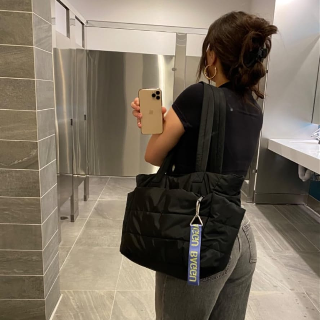 „Osoba z czarną torbą Softi na ramieniu, selfie w lustrze w łazience; widoczna zawieszka przy suwaku.”